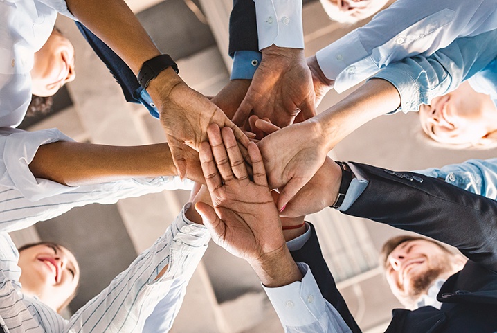 People piling hands on top of each other seen from below